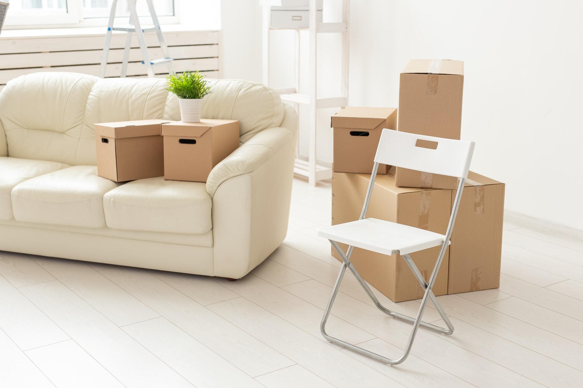 Folding chair sofa and boxes are in the new living room when residents move to a new apartment. The